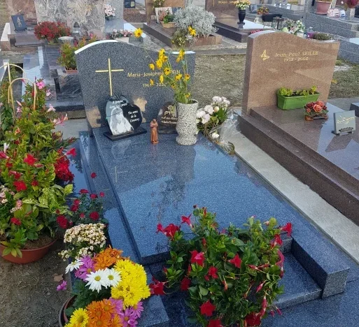 Pierre tombale en granit Lanhélin avec des fleurs dans un cimetière près d'Amiens (80)