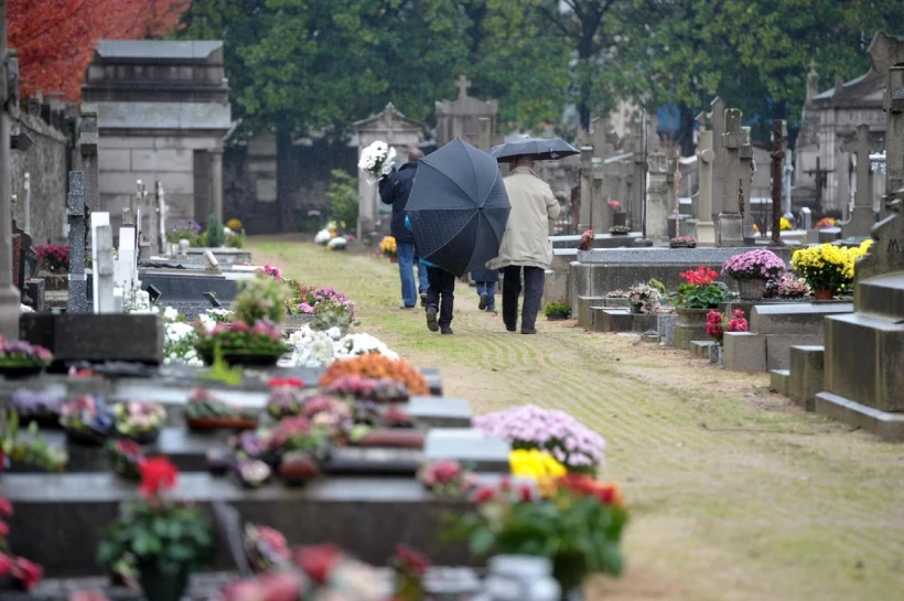 famille se recueillant sous la pluie sur une tombe