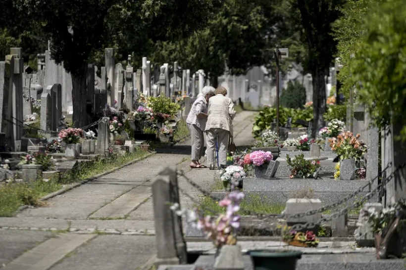 Personnes agées devant une concession funéraire dans un cimetière parisien